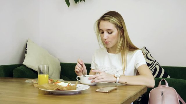 Healthy food. Close-up shot of young blonde woman eating vegetable soup at restaurant. 4K