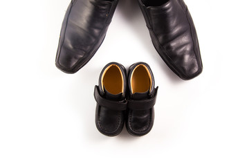 Big and small black leather shoes onwhite background. Father's day composition
