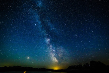 Starry sky and the milky way over the water.Bright star Mars.