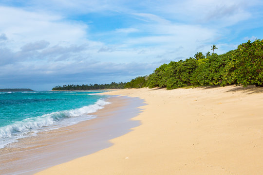 Shore of an azure, turquoise, blue lagoon. Waves, surf, swash at a remote empty idyllic sandy beach on Foa island, Haapai (Haʻapai or Ha'apai) group, Tonga, Oceania, South Pacific Ocean. Near Lifuka.