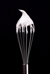 Metal whisk with whipped egg whites, isolated on black background. Clipping path.