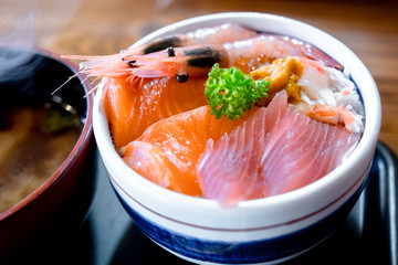close up Japanese food rice bowl with sashimi, fish, Salmon, and shrimp, seafood rice bowl on top of sashimi served fresh ingredient in Japanese style.