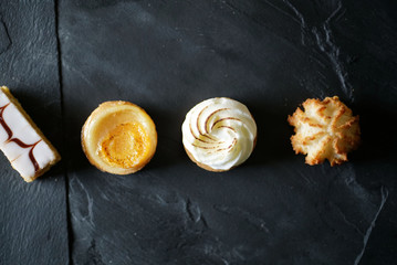 Top view of delicious French mini cakes lined up on black slate