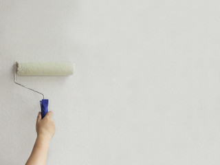 paint roller paints a white wall