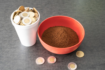 Styrofoam cup full of coins with red bowl of instant coffee
