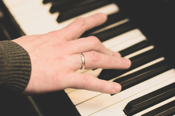 Obraz premium male hand of the musician with beautiful fingers playing the piano by pressing the keys. close up