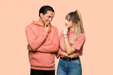 Young couple looking to the side with the hand on the chin over pink background
