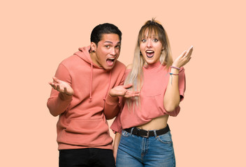 Fototapeta premium Young couple with surprise and shocked facial expression over pink background