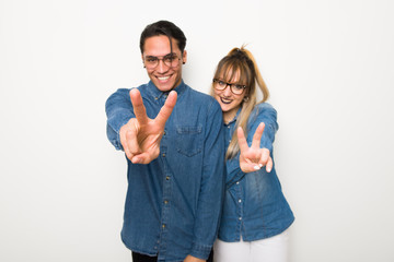 Young couple with glasses smiling and showing victory sign