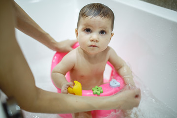 A little girl makes a happy bath with her mother.
