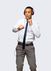 Young afro american businessman listening to music with headphones and dancing on isolated background