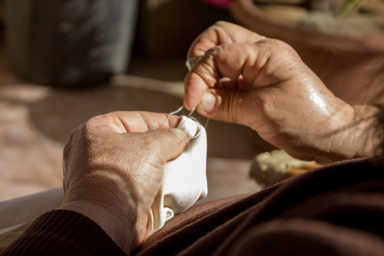 Manos de mujer utilizando un dedal y una aguja para coser