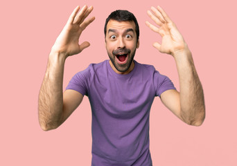 Handsome man with surprise and shocked facial expression on isolated pink background