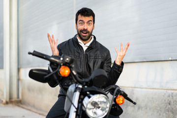 Fototapeta na wymiar Young man on a motorbike making surprise gesture