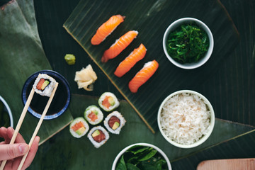 Sushi Maki Roll und Nigiri Lachs top view essen mit Stäbchen in der Hand von jungem Mann 