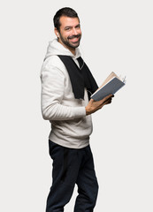 Sport man holding a book and enjoying reading over isolated grey background