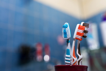 Three different colored tooth brushes in bathroom, shallow depth of field, copy space.