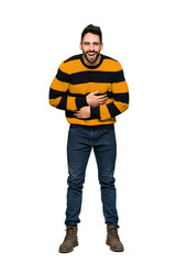 Full-length shot of Handsome man with striped sweater smiling a lot while putting hands on chest on isolated white background