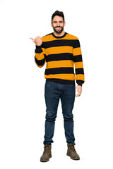 Naklejka premium Full-length shot of Handsome man with striped sweater pointing to the side to present a product on isolated white background