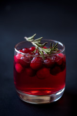 Cocktail with lingonberries and rosemary on a black background.