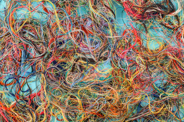 Colorful tangled threads on blue background. Closeup.