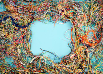 Colorful tangled threads on blue background. Closeup.