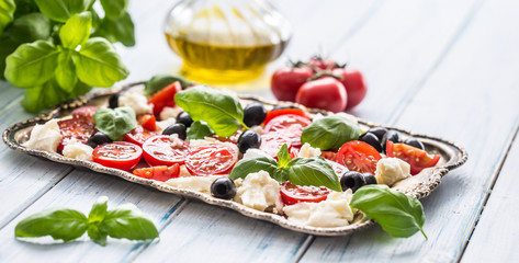 Caprese salad with mozzarella cheese ripe tomatoes olives and basil leaves. Italian or mediterranean healthy meal