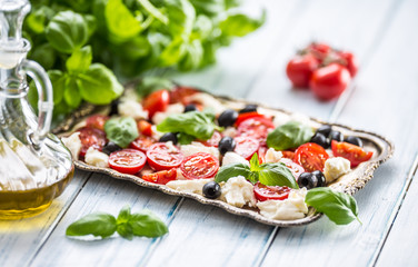 Caprese salad with mozzarella cheese ripe tomatoes olives and basil leaves. Italian or mediterranean healthy meal