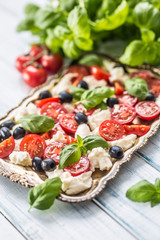 Caprese salad with mozzarella cheese ripe tomatoes olives and basil leaves. Italian or mediterranean healthy meal