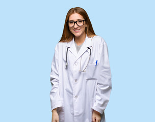 Redhead doctor woman with glasses and happy on isolated blue background