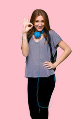 Redhead student woman showing an ok sign with fingers on isolated pink background