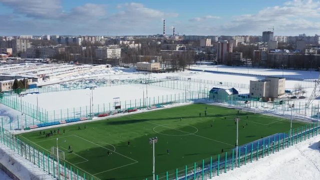 Aerial shot of amateur soccer field. shot of a modern football field with a white layout in winter. 4k footage