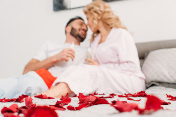 Laughing couple lying in bed with champagne glasses in valentine's day