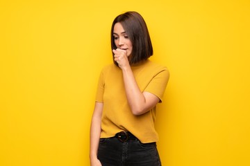 Young woman over yellow wall is suffering with cough and feeling bad