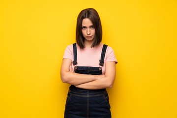 Young woman over yellow wall frustrated by a bad situation