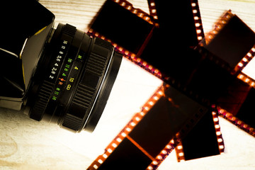 The concept of analog photography, the camera on the background of scattered negatives