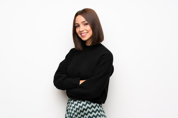 Young woman over white wall with arms crossed and looking forward