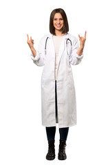 A full-length shot of a Young doctor woman making rock gesture over isolated white background