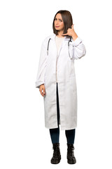 A full-length shot of a Young doctor woman making phone gesture and doubting over isolated white background