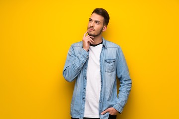 Handsome man over yellow wall thinking an idea while looking up