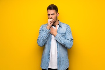 Handsome man over yellow wall is suffering with cough and feeling bad