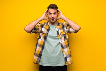 Fototapeta premium Handsome man over yellow wall surprised and shocked while looking right