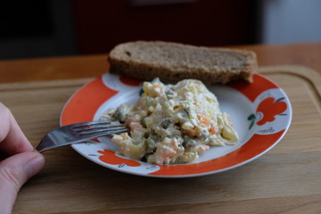Olivier salad on a plate you can see a piece of bread