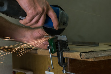 Men cuts a small metal sheet with an electric grinder