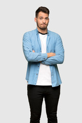 Handsome man making doubts gesture while lifting the shoulders over grey background