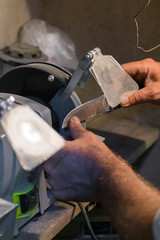 Man sharpens a knife on an electric grindstone