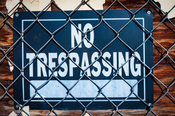 Close up on no trespassing sign behind wire fence