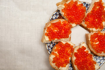 Sandwiches with red caviar and butter on a plate, lie on the table