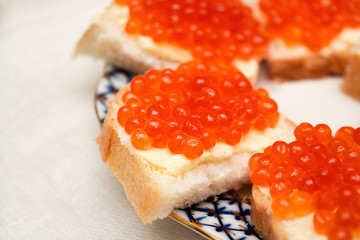 Sandwiches with red caviar and butter on a plate, lie on the table