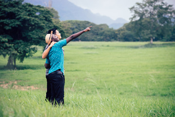 African man and asian man travelers standing in the green grass nature background.Concept of best friends